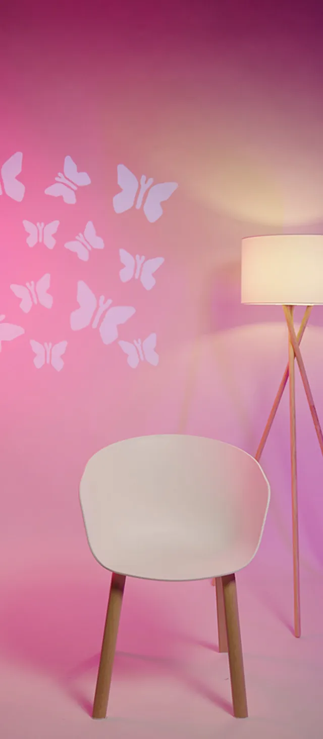A white chair against a pink backdrop lit with a butterfly light pattern, one of several interchangeable looks